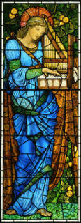 stained glass of Saint Ceclia standing and playing a small hand-held organ